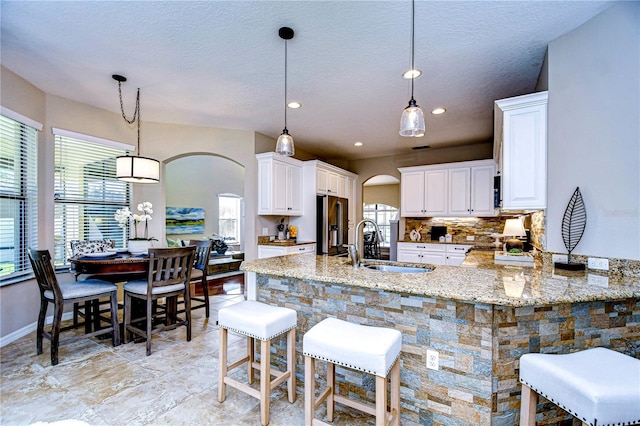 kitchen featuring decorative light fixtures, white cabinets, a kitchen bar, and kitchen peninsula