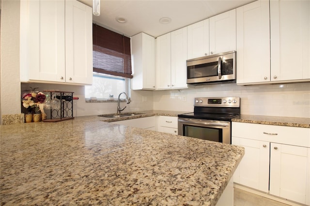 kitchen featuring white cabinets, stainless steel appliances, light stone countertops, and sink