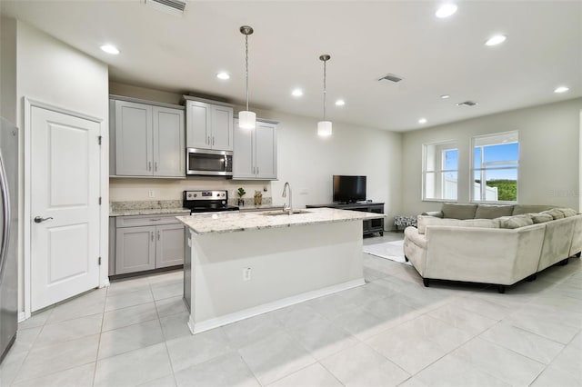 kitchen featuring appliances with stainless steel finishes, sink, pendant lighting, a center island with sink, and gray cabinets