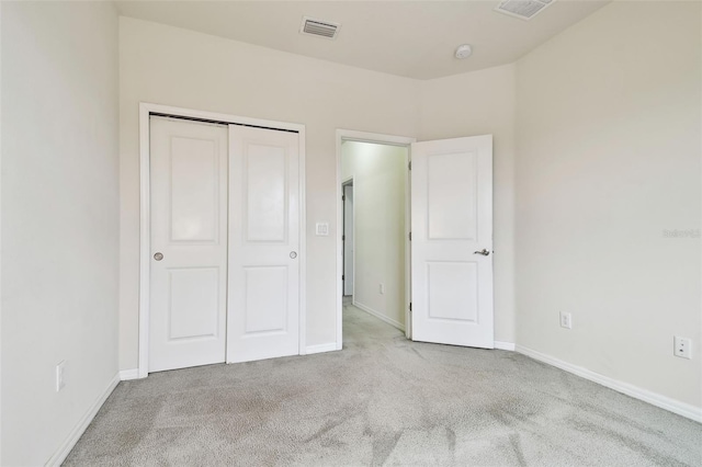 unfurnished bedroom with light colored carpet and a closet