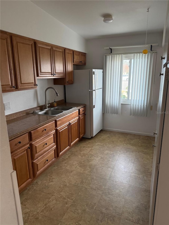 kitchen featuring sink, hanging light fixtures, white fridge, and vaulted ceiling