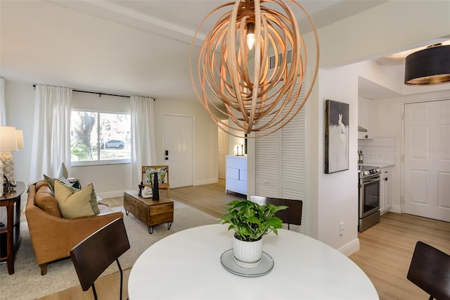 dining room with beamed ceiling and light hardwood / wood-style flooring