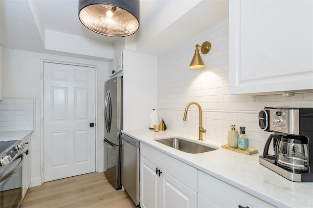 kitchen featuring tasteful backsplash, white cabinetry, sink, and stainless steel appliances