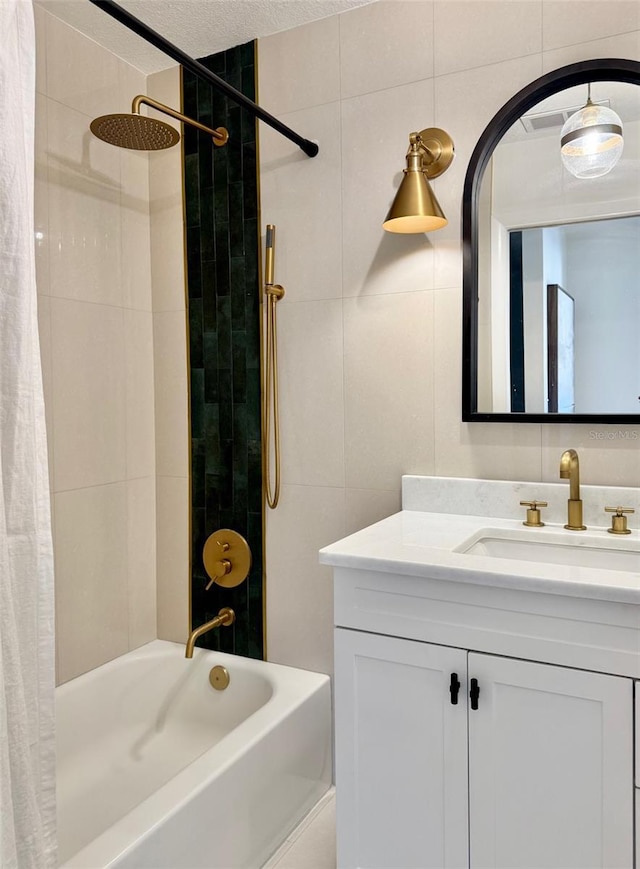 bathroom with a textured ceiling, shower / tub combo with curtain, vanity, and tile walls