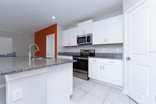 kitchen with sink, appliances with stainless steel finishes, a kitchen island with sink, and white cabinetry