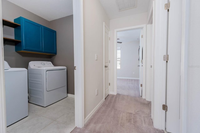 laundry room with independent washer and dryer, cabinets, and light tile patterned flooring