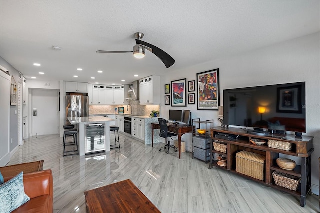 living room with light wood-type flooring, wine cooler, ceiling fan, and sink