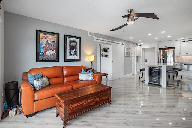 living room featuring a barn door, beverage cooler, and ceiling fan