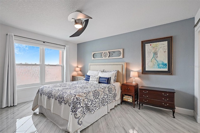 bedroom with a textured ceiling, light hardwood / wood-style floors, and ceiling fan