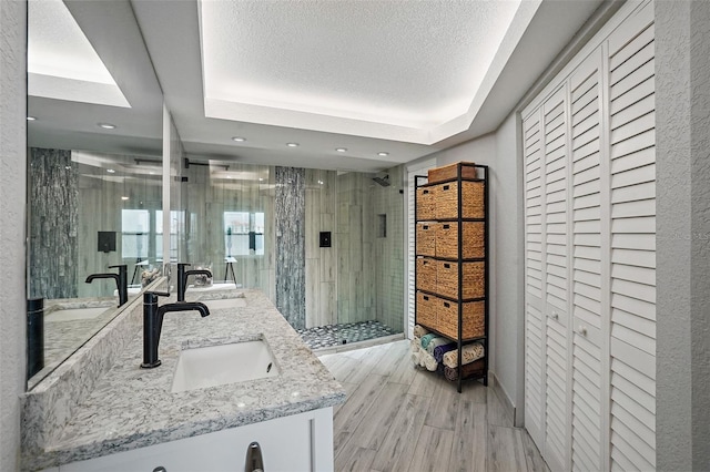 bathroom with a shower with door, vanity, wood-type flooring, and a textured ceiling