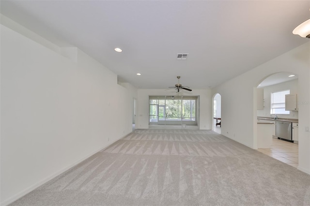 unfurnished living room with light colored carpet, ceiling fan, and sink