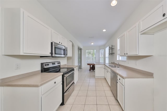 kitchen with kitchen peninsula, appliances with stainless steel finishes, light tile patterned floors, and white cabinetry