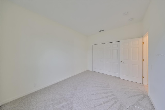 unfurnished bedroom with a closet and light colored carpet