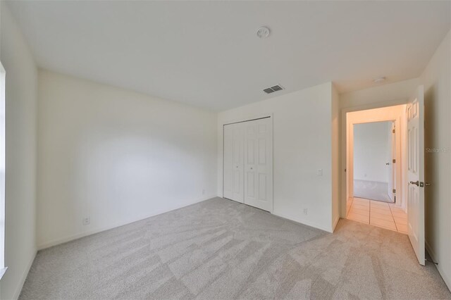 unfurnished bedroom featuring light carpet and a closet