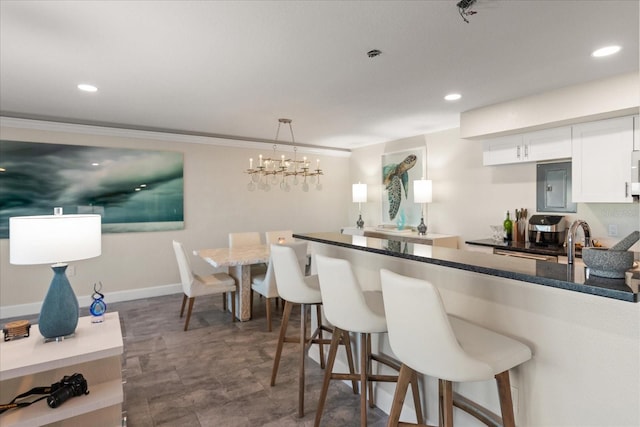 kitchen with a breakfast bar area, electric panel, white cabinetry, and pendant lighting