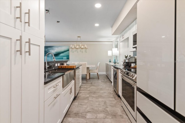 kitchen with ornamental molding, stainless steel appliances, sink, a notable chandelier, and white cabinetry