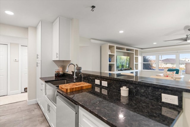 kitchen featuring white cabinets, sink, stainless steel dishwasher, ceiling fan, and dark stone countertops