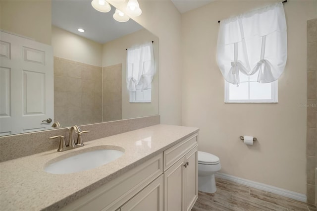 bathroom with toilet, vanity, plenty of natural light, and hardwood / wood-style floors