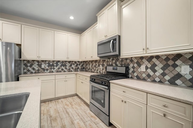 kitchen featuring appliances with stainless steel finishes, decorative backsplash, light hardwood / wood-style flooring, and sink