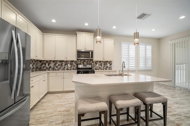 kitchen featuring pendant lighting, a kitchen bar, stainless steel appliances, sink, and a center island with sink