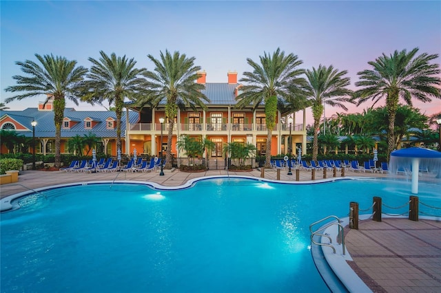 pool at dusk featuring pool water feature and a patio area