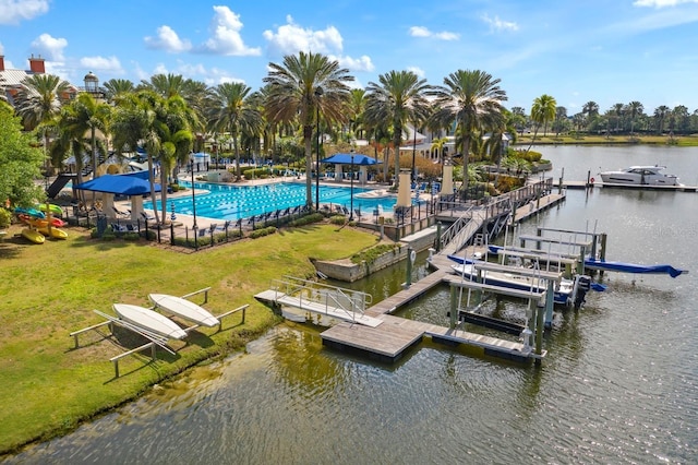 view of dock with a community pool, a water view, and a yard