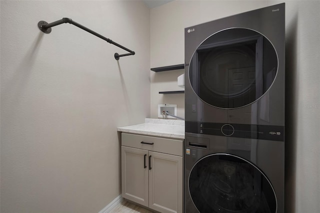 washroom with cabinets and stacked washer and clothes dryer