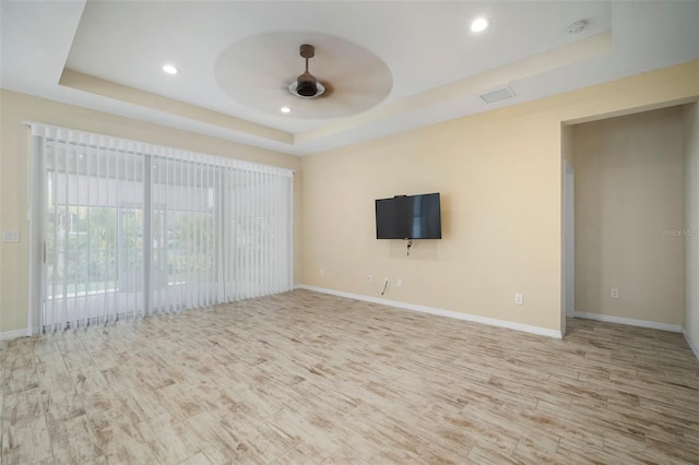 unfurnished living room with ceiling fan, hardwood / wood-style floors, and a raised ceiling