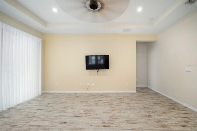 unfurnished living room with a raised ceiling, ceiling fan, and light hardwood / wood-style flooring