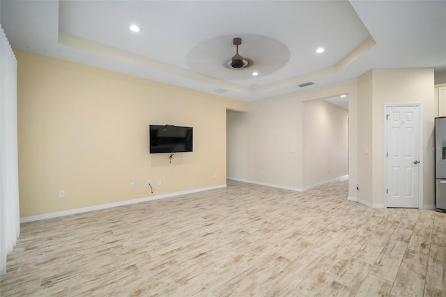 unfurnished living room featuring ceiling fan, light hardwood / wood-style flooring, and a raised ceiling