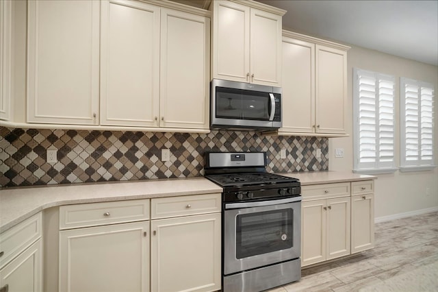 kitchen featuring stainless steel appliances, decorative backsplash, cream cabinetry, and light hardwood / wood-style flooring