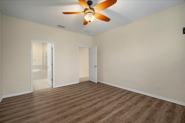 unfurnished bedroom with ceiling fan, dark hardwood / wood-style floors, and connected bathroom