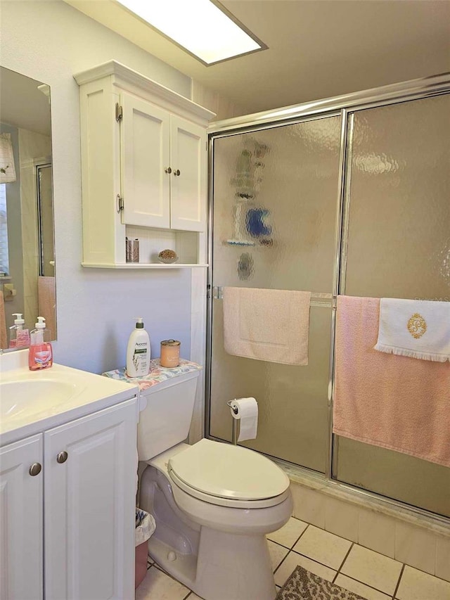 bathroom with toilet, vanity, tile patterned floors, and walk in shower