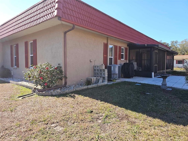 view of property exterior featuring central air condition unit, a sunroom, and a yard