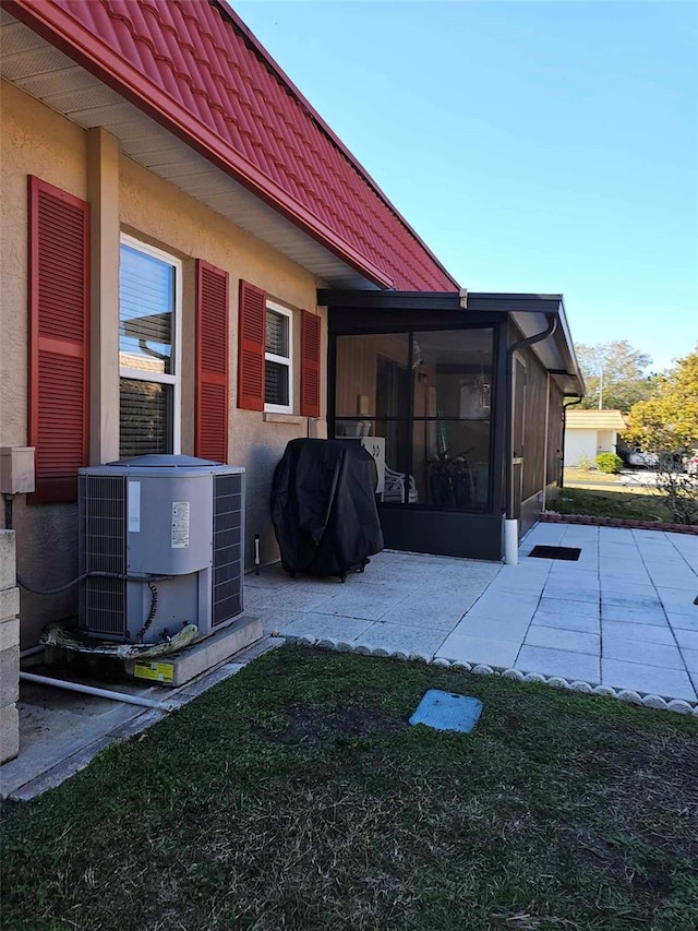 exterior space featuring a sunroom, a patio, a lawn, and central air condition unit