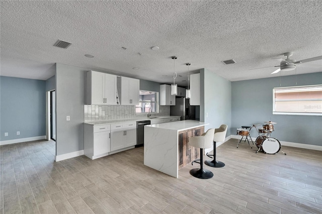 kitchen with pendant lighting, ceiling fan, appliances with stainless steel finishes, tasteful backsplash, and white cabinetry