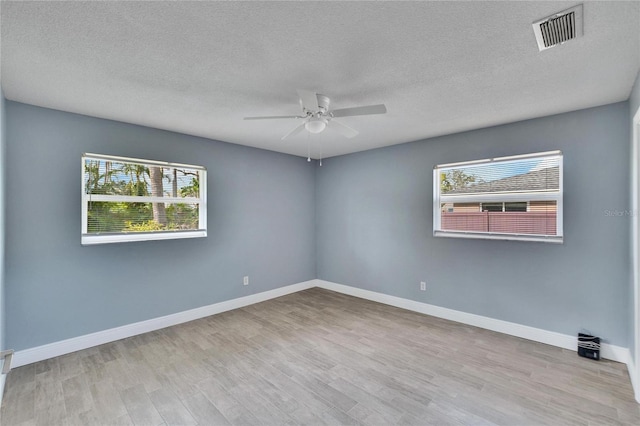 unfurnished room featuring ceiling fan, a healthy amount of sunlight, a textured ceiling, and light wood-type flooring