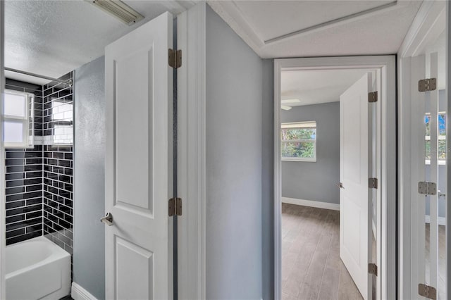 bathroom with wood-type flooring, a textured ceiling, and tiled shower / bath combo