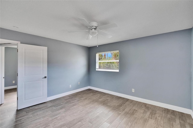 empty room featuring ceiling fan, light hardwood / wood-style flooring, and a textured ceiling