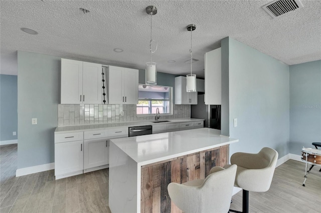 kitchen with tasteful backsplash, white cabinets, hanging light fixtures, and appliances with stainless steel finishes