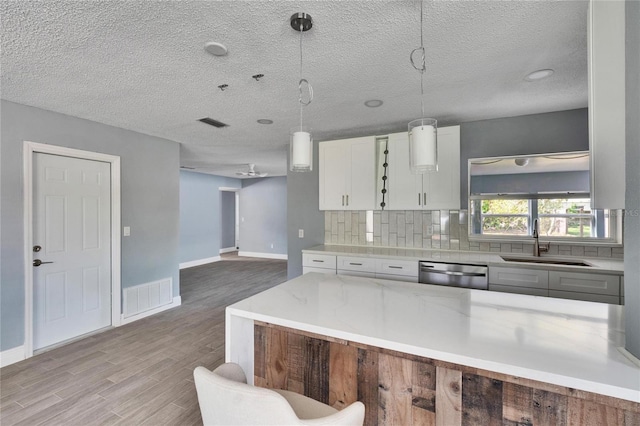 kitchen with white cabinetry, dishwasher, sink, pendant lighting, and decorative backsplash