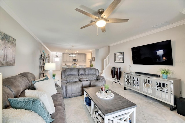 tiled living room with ornamental molding and ceiling fan with notable chandelier