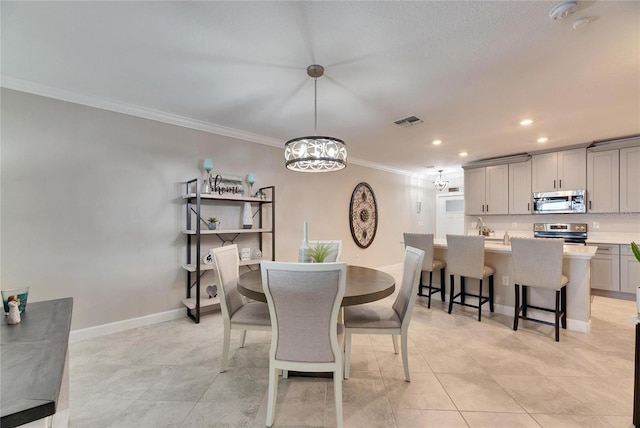 tiled dining area featuring an inviting chandelier and ornamental molding