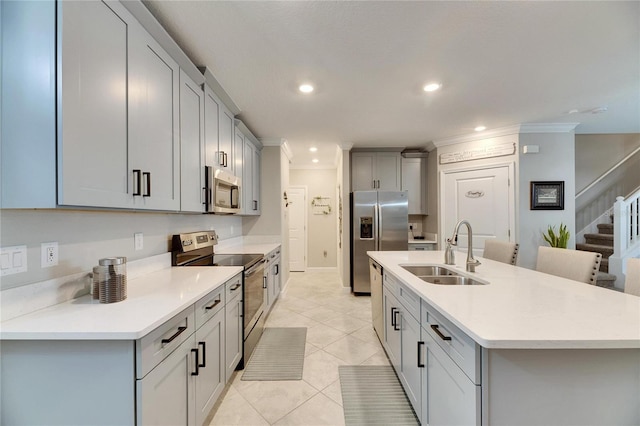 kitchen with appliances with stainless steel finishes, an island with sink, sink, light tile patterned flooring, and gray cabinetry