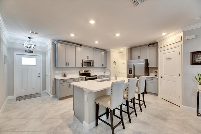 kitchen featuring appliances with stainless steel finishes, gray cabinetry, a center island with sink, and sink