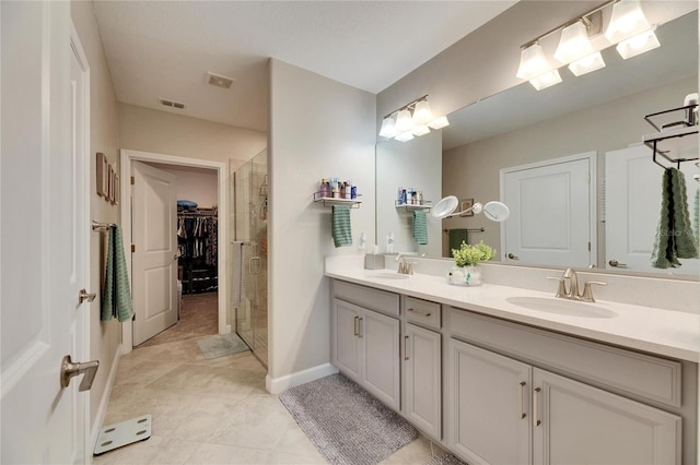 bathroom featuring a shower with shower door, vanity, and tile patterned flooring