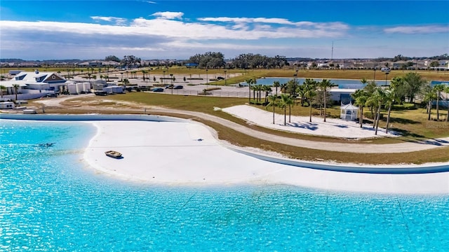 view of swimming pool with a water view and a beach view