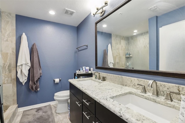 bathroom with tile patterned floors, tiled shower, vanity, and toilet