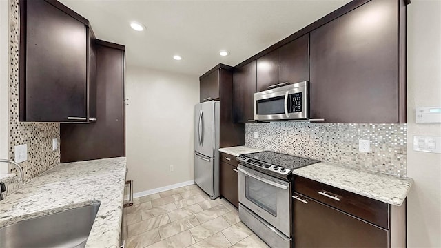 700 S Harbour Island Blvd Unit 226, Tampa, FL 33602 - kitchen featuring stainless steel appliances, a sink, dark brown cabinets, baseboards, and light marble finish floors
