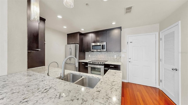 700 S Harbour Island Blvd Unit 226, Tampa, FL 33602 - kitchen featuring appliances with stainless steel finishes, a sink, light wood-style floors, decorative backsplash, and light stone countertops